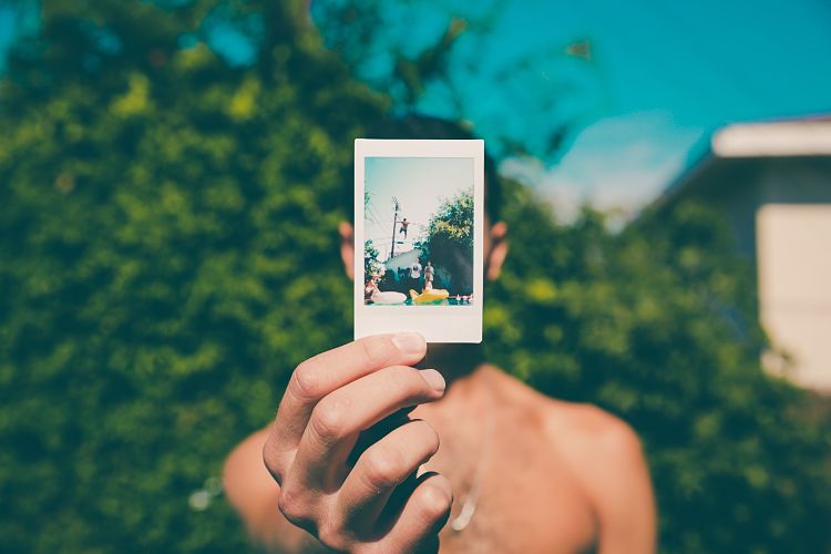 Hombre sosteniendo una foto polaroid en la mano